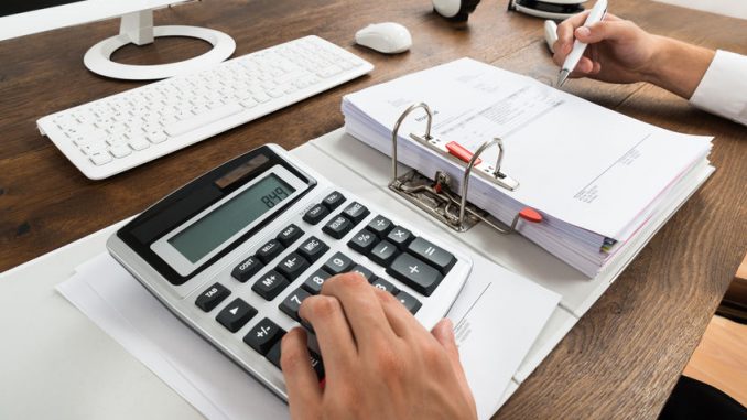 47216001 - close-up of businessman checking invoice with calculator at desk